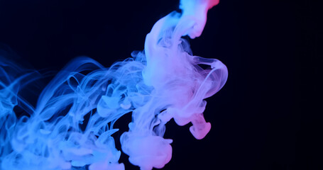 Fototapeta premium Ethereal blue smoke swirls elegantly against a dark background, creating a mysterious and atmospheric scene.