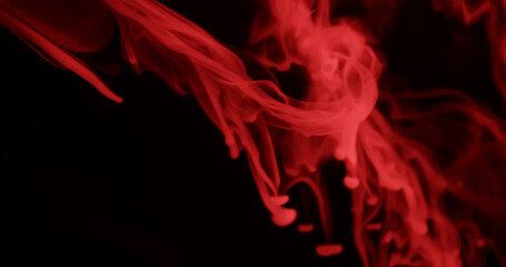 Obraz premium Ethereal red smoke swirls elegantly against a dark background, creating a mysterious and atmospheric scene.