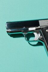 Naklejka premium Semi Automatic Handgun Isolated on Teal Background with Metallic Texture For Law Enforcement Training and Crime Drama Visuals Featuring Hard Studio Lighting and Copy Space