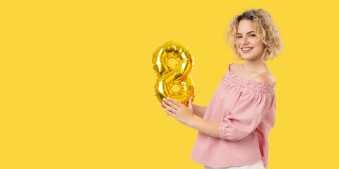 Fototapeta premium Woman smiles and holds a golden number balloon in celebration