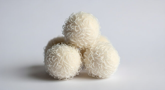 Three white coconut truffles or Raffaello sweets stacked together on a white background.