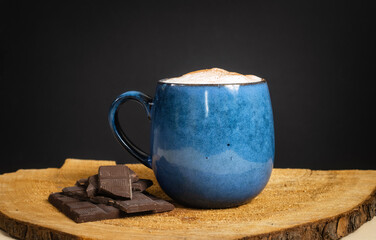A cup of delicious, aromatic coffee with chocolate pieces on a dark background