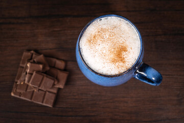 A cup of delicious, aromatic coffee with chocolate pieces on a dark background