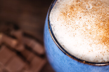 A close-up of a cup of delicious, aromatic coffee with foam on a dark background