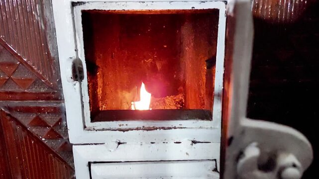 Warm flames flicker inside a wood stove set in a vintage tiled hearth, creating a cozy atmosphere as the fire crackles - capturing comfort, heat, and timeless home ambiance