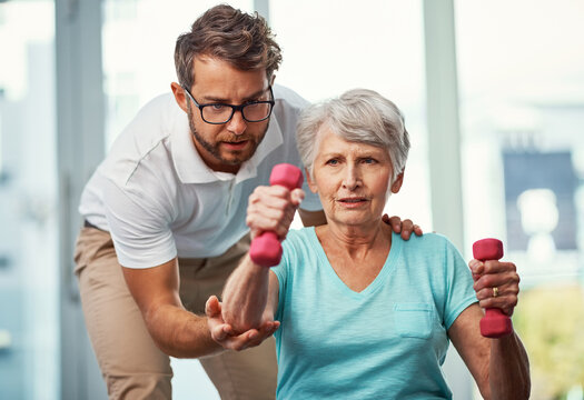 Weights, physical therapist and senior woman with exercise, rehabilitation or recovery with support. Healthcare, dumbbells and physiotherapist with elderly patient for arm muscle training in clinic.
