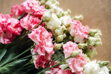 Pink and white lisianthus flowers rest in close up view on neutral surface. Floral design process, creative workspace, artisanal skills, flower workshop.