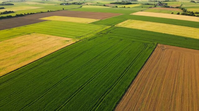 Scenic aerial flight over a vast patchwork of colorful agricultural fields.