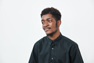 Obraz premium Young black man with dark skin wearing black shirt looking aside with thoughtful expression on white background. Portrait of African ethnicity male with casual style and short hair.