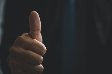 Sign of approval shows a man hand pose with a thumbs up gesture in a closeup, this positive sign...