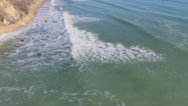 Overhead seascape shows foamy waves mixing with emerald water forming organic shapes and smooth flowing motion textures