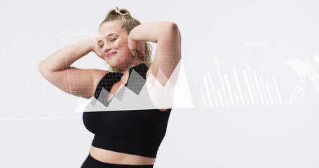 Standing woman wearing black crop top and high-waist bottoms in studio, with digital charts overlay