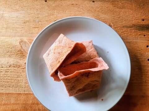 Traditional Maluku souvenir snack known as sagu lempeng served on a white plate on wooden table,Indonesian local food and cultural heritage.