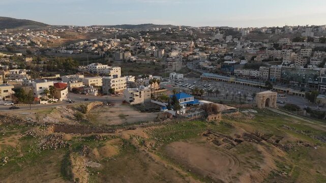 breathtaking aerial perspective of the Greco-Roman city of Jerash at sunrise, highlighting the well-preserved Oval Plaza and its surrounding columns in morning light