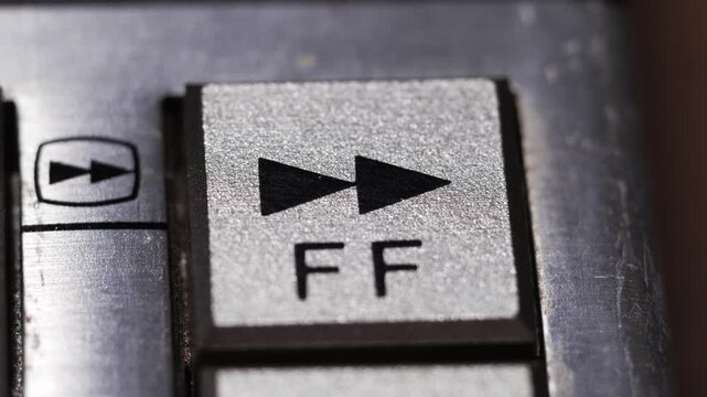 Macro close up of finger pressing silver fast forward button with double triangle