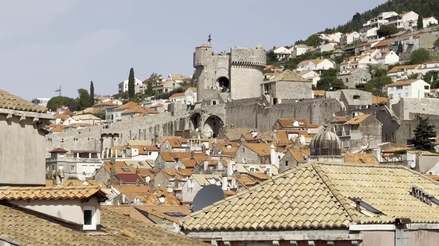 Cinematic cityscape view over Dubrovnik Old Town rooftops from the city walls with Minceta Tower rising above historic limestone buildings with terracotta rooftops