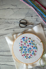 Hand-embroidered spring flowers in pastel pink, blue, and green tones. Close-up of floral design in an embroidery hoop, perfect for Easter, spring decor, and DIY hobby projects celebrating creativity 