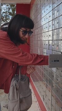 A woman opens her mailbox and takes out her mail. Mail delivery concept.