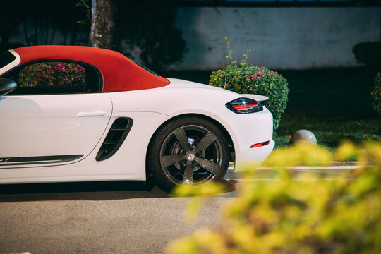 White Porsche 718 Boxster T convertible with red roof at night