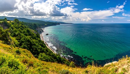 A coastal landscape showcases a lush green cliffside meeting a turquoise sea under a dynamic, cloudy sky