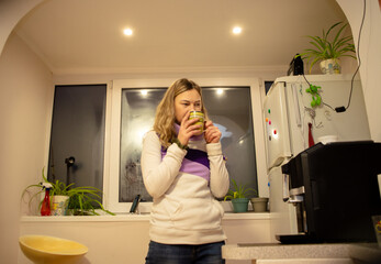 Middle-Aged Woman Enjoying a Hot Drink in a Cozy Home Kitchen in the Evening