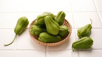 A pile of green chayote squash on bamboo plate
