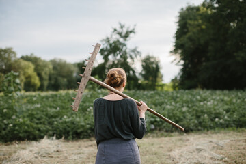 Woman carrying rake walking through ukrainian field