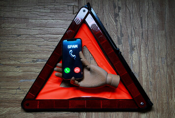 Tel&eacute;fono spam con n&uacute;mero oculto y desconocido, mano de madera y peligro advertencia con tri&aacute;ngulo reflectante de emergencia
