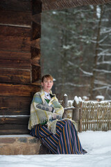 Latvian woman in traditional dress poses in a village in winter. Riga, Latvia.