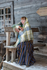 Latvian woman in traditional dress poses in a village in winter. Riga, Latvia.