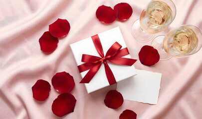 Romantic Valentine Gift Box with Champagne Glasses and Rose Petals on Pink Silk Background with Blank Card for Copy Space