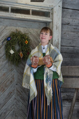 Latvian woman in traditional dress poses in a village in winter. Riga, Latvia.