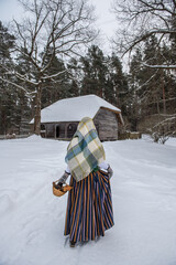 Latvian woman in traditional dress poses in a village in winter. Riga, Latvia.