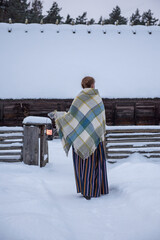 Latvian woman in traditional dress poses in a village in winter. Riga, Latvia.