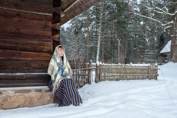 Latvian woman in traditional dress poses in a village in winter. Riga, Latvia.