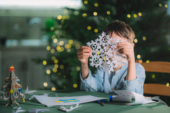 Child making paper snowflake Christmas decorations indoors