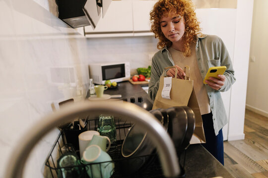 Woman checking parcel in kitchen at home