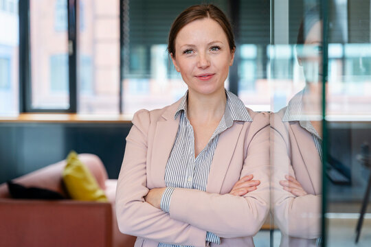 Confident entrepreneur posing in modern office with arms crossed