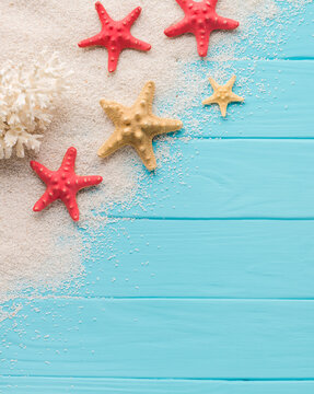 Aerial view of beachthemed items, starfish, and sand on a blue wooden background