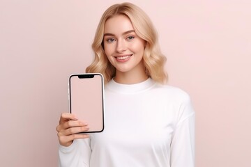 Naklejka premium Blonde woman smiling, holding smartphone with blank screen for app or product display