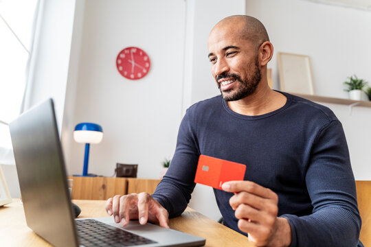 Smiling buyer making secure online payment on laptop indoors