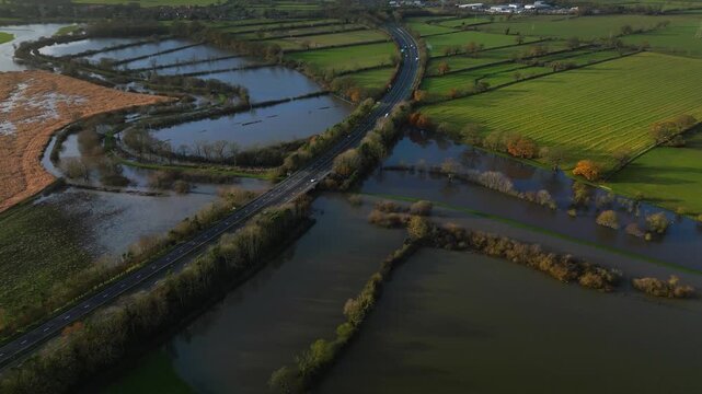 Aerial view of Malton bypass A64 dual carraigeway with cars driving runs over a flooded River Derwent and surrounding green fields on sunny winter day