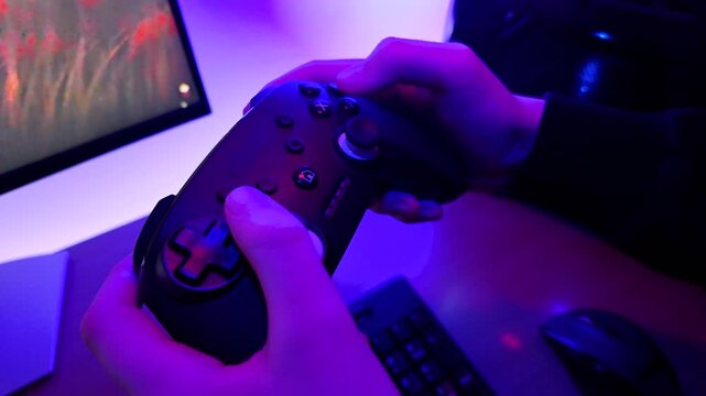 Close up of gamer hands using controller during video game session with moody lighting and immersive digital environment