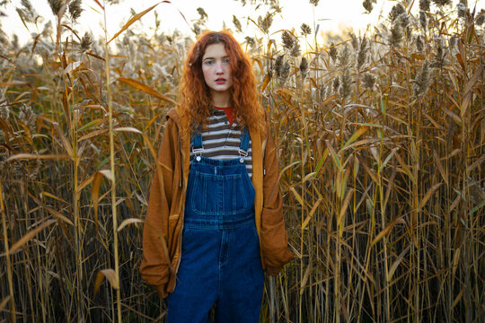 Red haired woman in denim overall and orange hoodie outdoors in fog