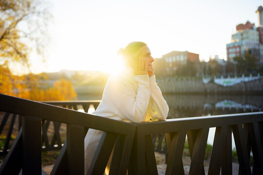 Woman leaning on embankment railing in golden morning light outdoors