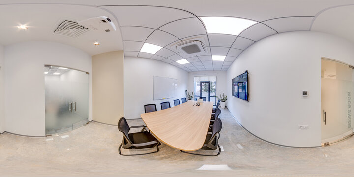 Full 360 degree view of a bright and clean corporate meeting room featuring a large wooden table black chairs white walls and modern office equipment.
