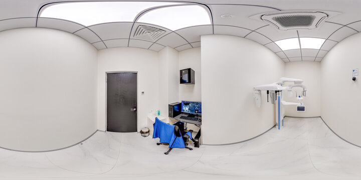A clean 360 degree equirectangular view of a professional dental diagnostic room featuring a panoramic xray machine, medical computer desk, and sterile clinical interior.