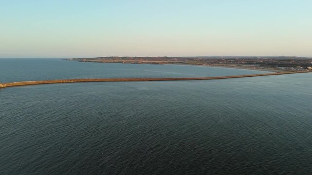 Sunset casts a warm glow over Tynemouth Pier along the North Sea at dusk