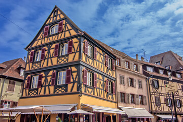 Colorful historic timber houses with flowers lining a narrow street in Colmar.