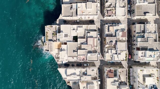 Aerial view of the buildings along the coastline contrasting with the turquoise waters of the sea, Polignano a Mare, Apulia, Italy.